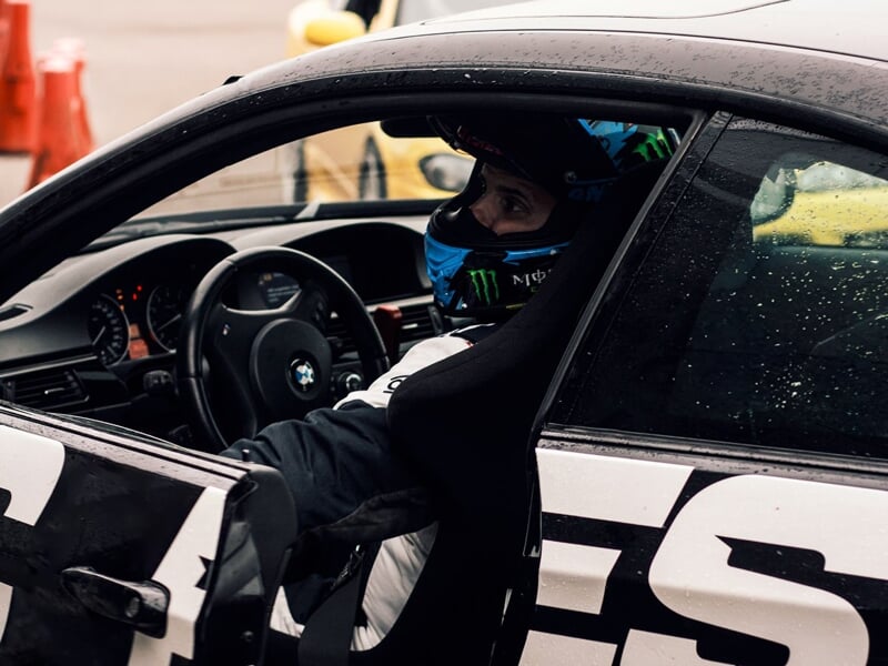 Un homme en tenue de pilote, assis dans une BMW noire, en train d'ouvrir la portière.