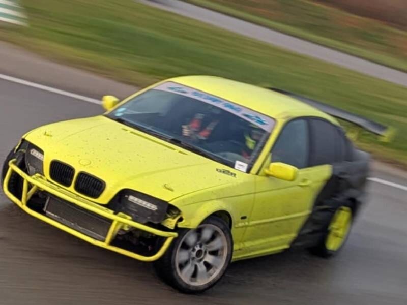 BMW jaune fluo et noire en plein drift sur un circuit.