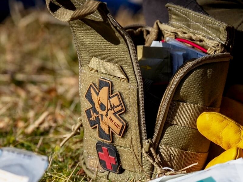 Trousse de premiers secours militaire ouverte, avec gants jaunes visibles, prête pour intervention rapide.