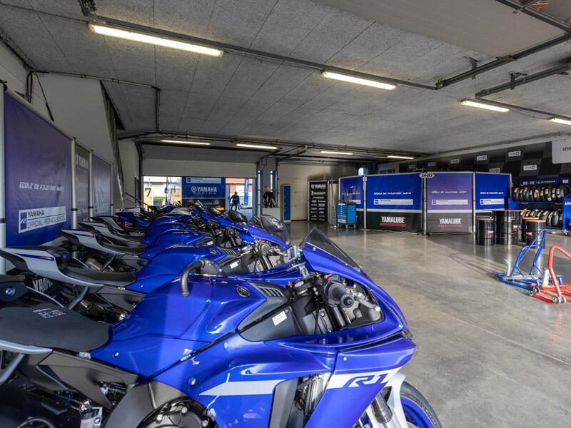 Atelier de course avec une rangée de motos sportives Yamaha bleues alignées et prêtes pour la course