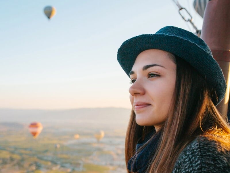une femme regarde l'horizon à bord de la nacelle d'une montgolfière