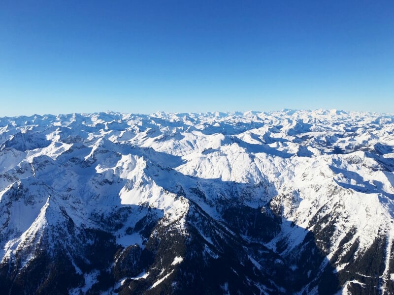 Panorama de montagnes enneigées sous un ciel clair, photographié depuis une montgolfière.