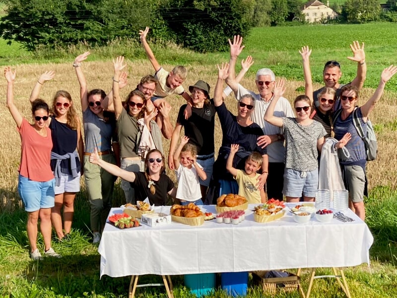 Groupe de personnes souriantes posant devant une table de pique-nique en plein air en montagne.