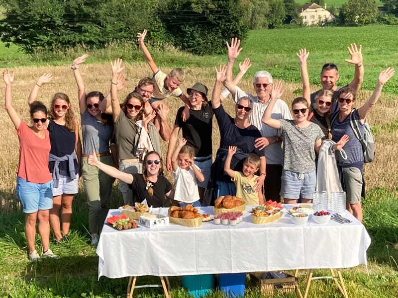 Un groupe de personnes souriantes lève les bras autour d'une table 