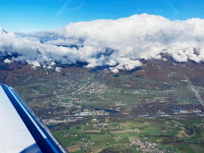 Paysage vu d'un avion en vol montrant une vallée verte avec des villages et des collines.