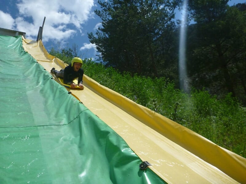 Personne glissant sur un toboggan aquatique vert dans un parc aquatique en plein air.