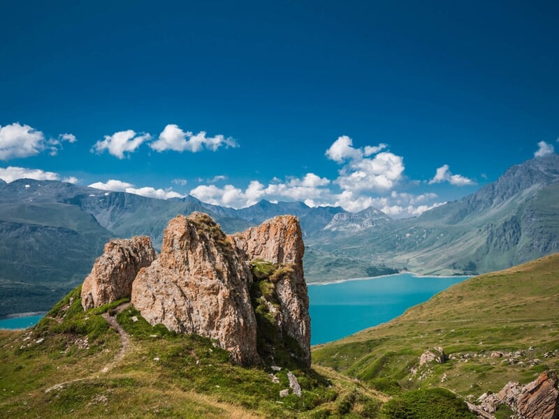 Vue depuis un kayak sur un lac de montagne avec des sommets rocheux et ciel bleu.