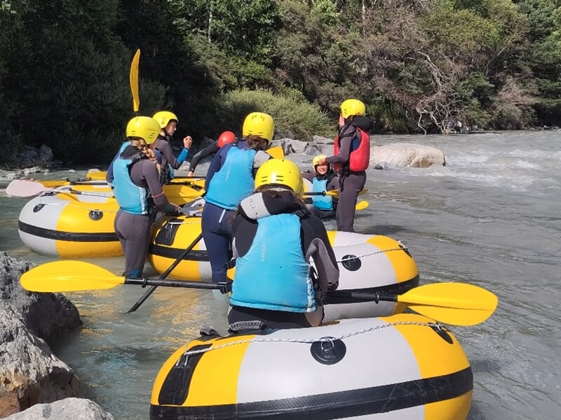Groupe de personnes sur la rive de l'Arc avec matériel de river tubing