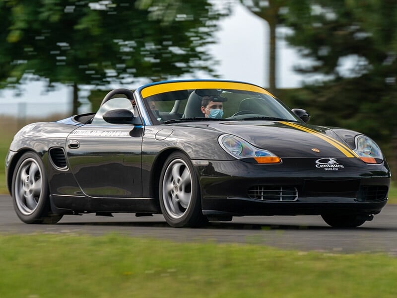 Un enfant au volant d'une Porsche Boxster noire