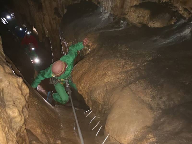 Des gens pratiquant la spéléologie s'enfoncent sous terre avec des cordages.