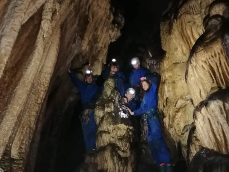 Un groupe de personnes habillées de combinaisons bleues posent dans une grotte.