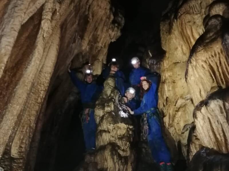 Un groupe de personnes habillées de combinaisons bleues posent dans une grotte.