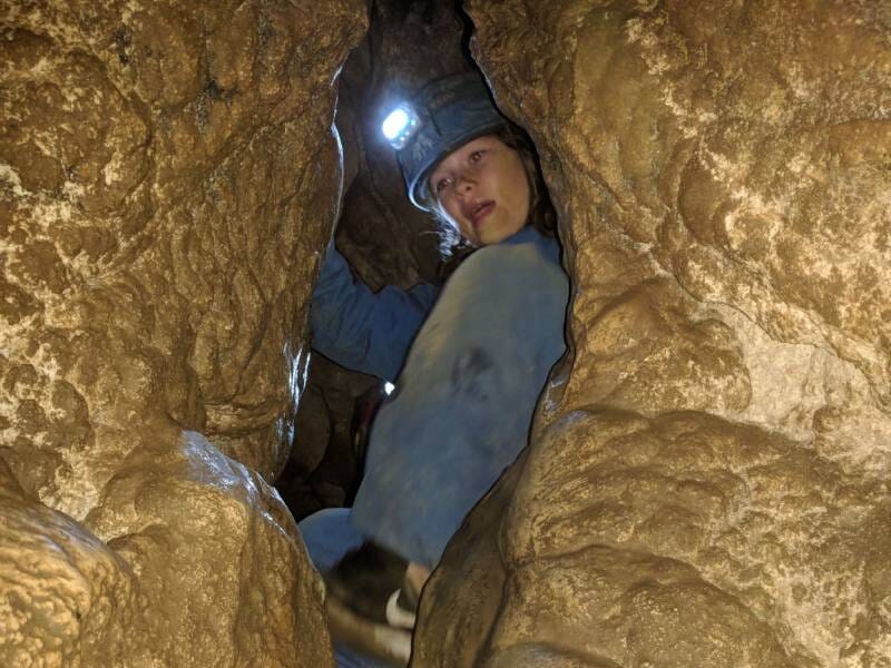 Une jeune personne vêtue de bleu s'apprête à passer à travers un passage étroit.