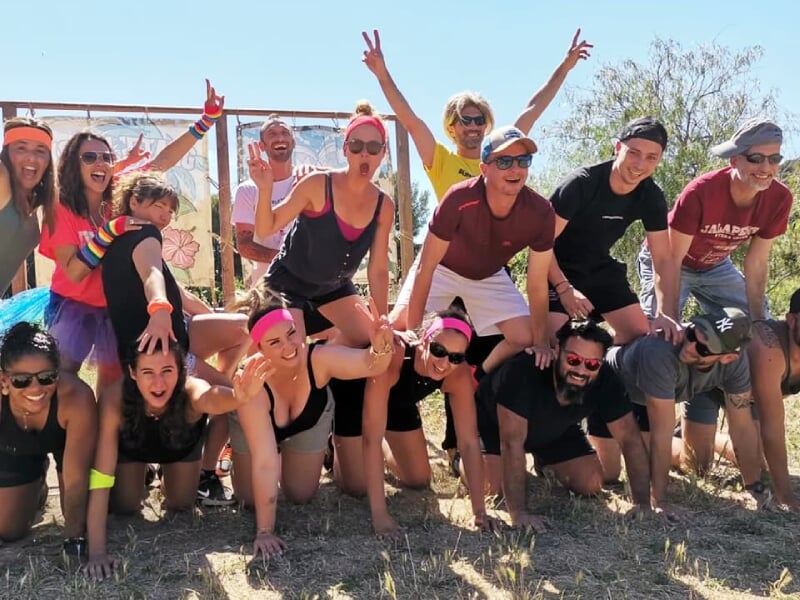 Groupe de personnes souriantes posant ensemble en plein air lors d'une activité sportive ou ludique sous le soleil.