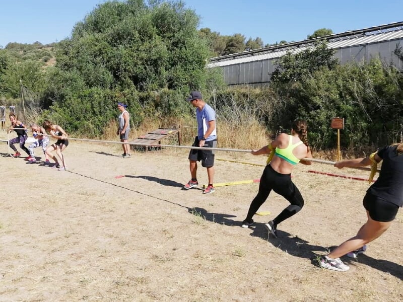 Groupe de personnes tirant une corde lors d'un jeu de tir à la corde sur un terrain sec en plein air.