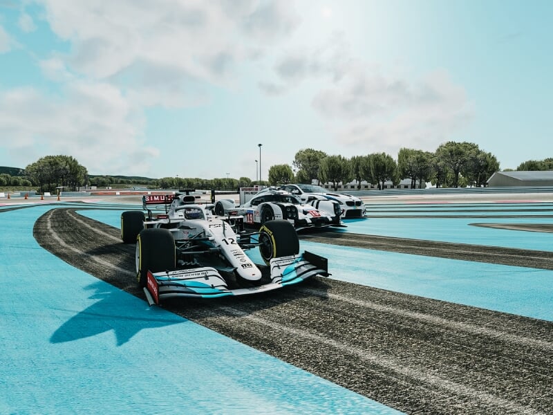 Deux voitures de Formule 1 en pleine compétition sur un circuit au sol bleu, se disputant la première place sous un ciel légèrement nuageux, symbolisant l'intensité de la course automobile