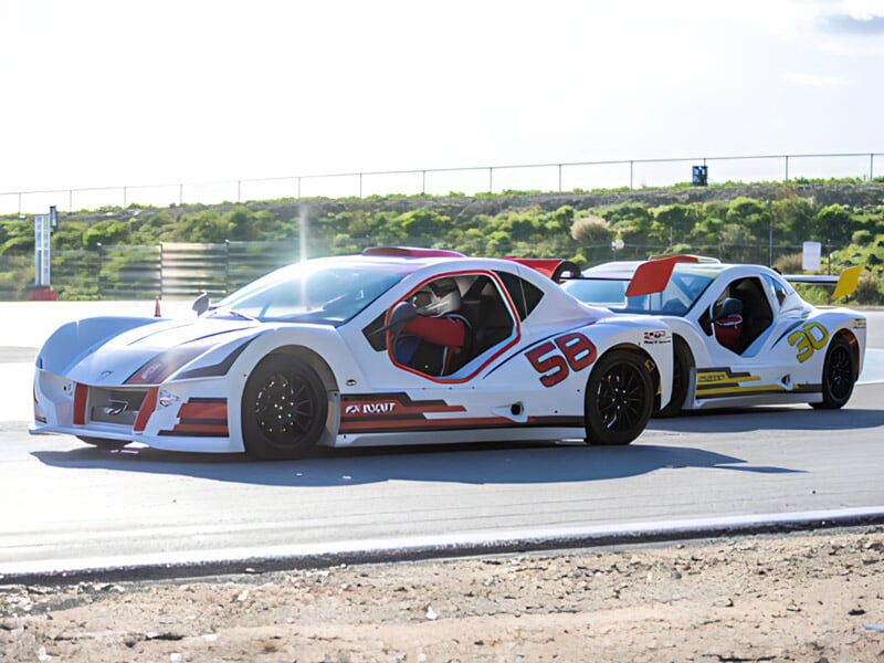 Deux voitures de course blanches avec détails rouges et jaunes sur circuit, en pleine action.
