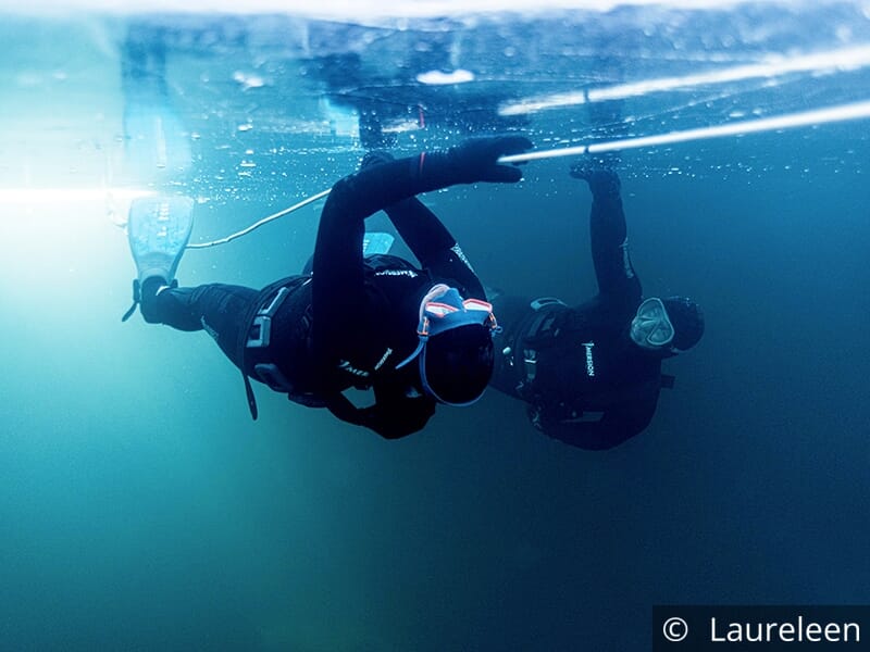 Deux plongeurs explorant sous la glace attachés à une corde.