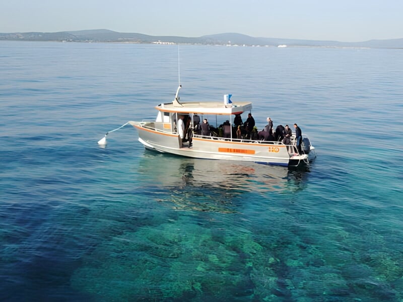 Bateau de plongée blanc avec plusieurs personnes à bord, flottant sur une mer calme et transparente à Sainte-Maxime.