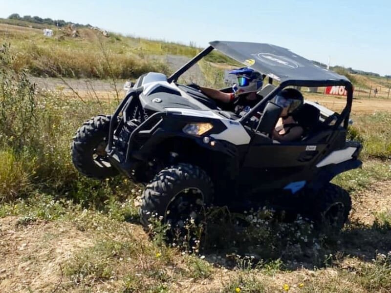 Conduite d'un buggy tout-terrain noir et blanc sur un sentier herbeux avec un passager à bord.