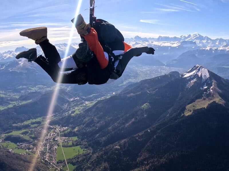 Deux personnes en chute libre lors d'un saut en parachute au-dessus des montagnes enneigées de Megève, ciel clair.