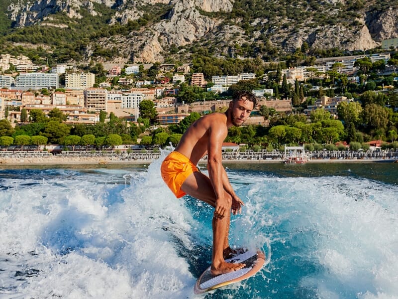 Un homme faisant du wake surf avec la ville de Monaco en fond