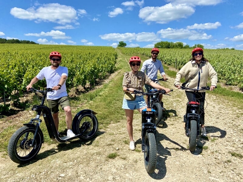 Groupe de 4 personnes en trottinette électrique au milieu des vignes