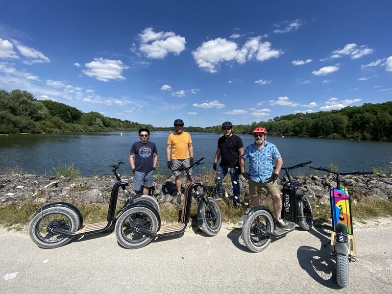 Groupe de personnes en trottinette électrique devant le lac Amance