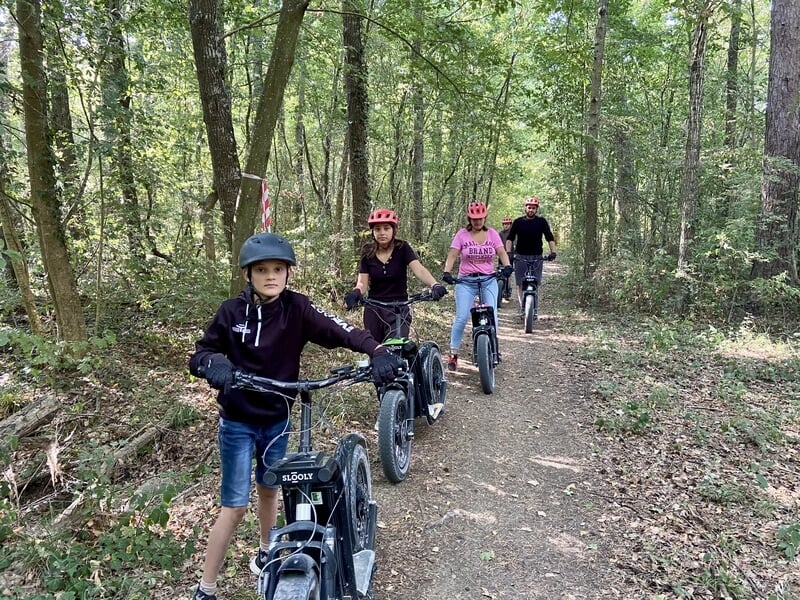 Groupe de jeunes en trottinette électique sur un sentier dans les bois
