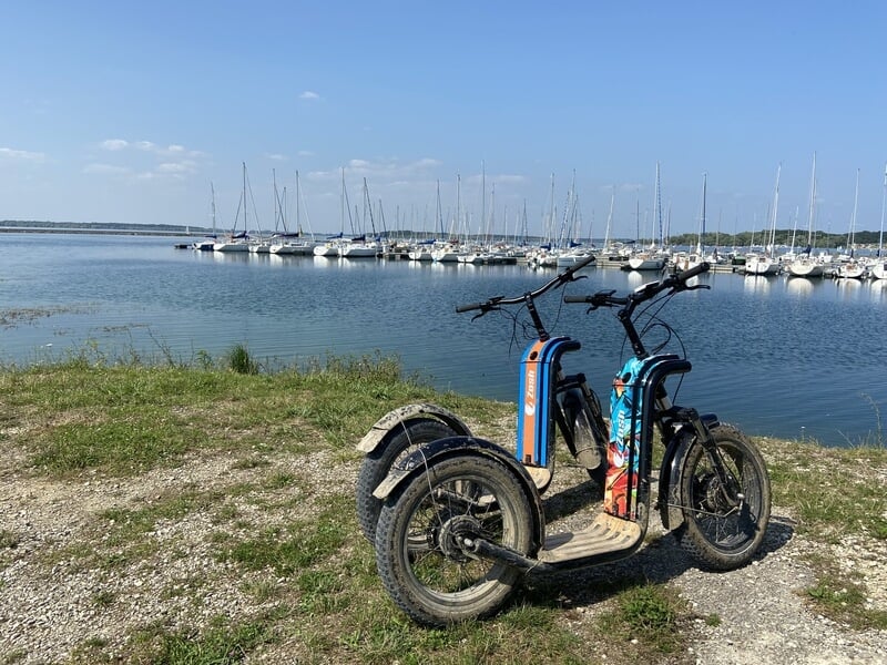 Trottinettes électriques au bord du lac d'Orient avec bateaux en arrière plan