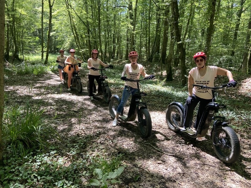 Groupe de personne pratiquant la trottinette électrique sur un sentier de forêt