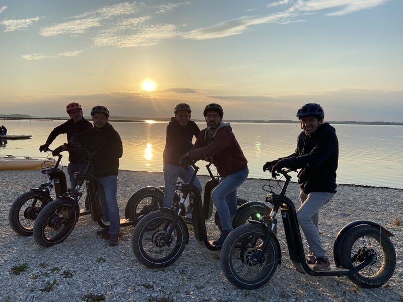 Groupe de personnes en trottinette électrique près du lac d'Orient au coucher du soleil