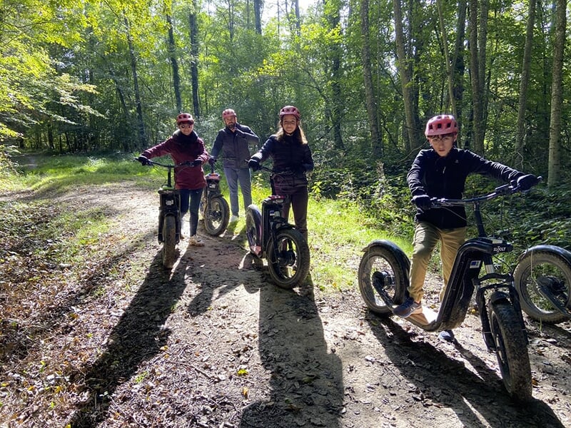 Un groupe de touristes posent devant leurs trottinettes lors d'une balade sportive en forêt