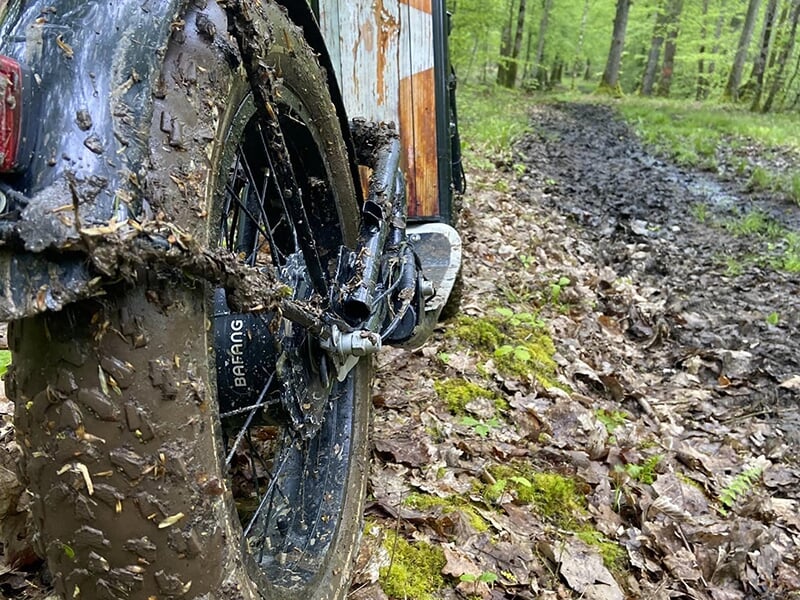 Gros plan sur la roue arrière d'une trottinette électrique sur un chemin boueux dans une forêt