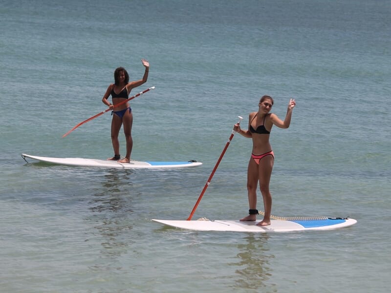 deux personnes posent debout sur leur paddle
