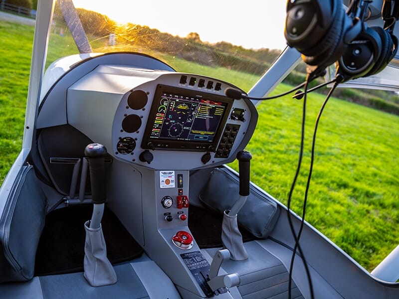 Tableau de bord moderne d’un avion léger avec instruments numériques au coucher du soleil.