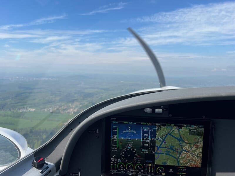 Cockpit d'un avion ULM en vol avec instruments de navigation visibles et paysage flou à travers le pare-brise.