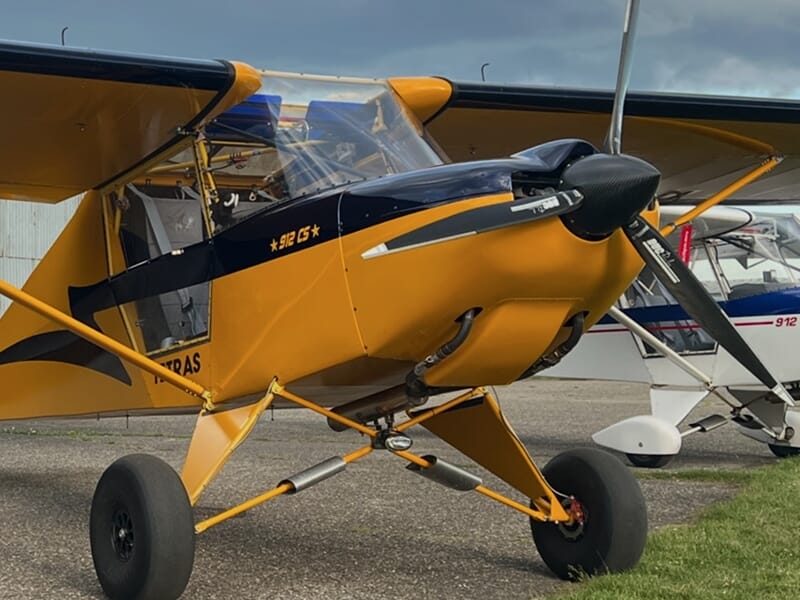 Petit avion jaune et noir stationné sur l'aérodrome de Mulhouse Habsheim sous un ciel nuageux, prêt pour un vol d'initiation.
