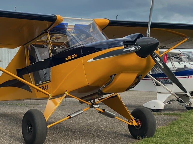 Petit avion jaune et noir stationné sur l'aérodrome de Mulhouse Habsheim sous un ciel nuageux, prêt pour un vol d'initiation.