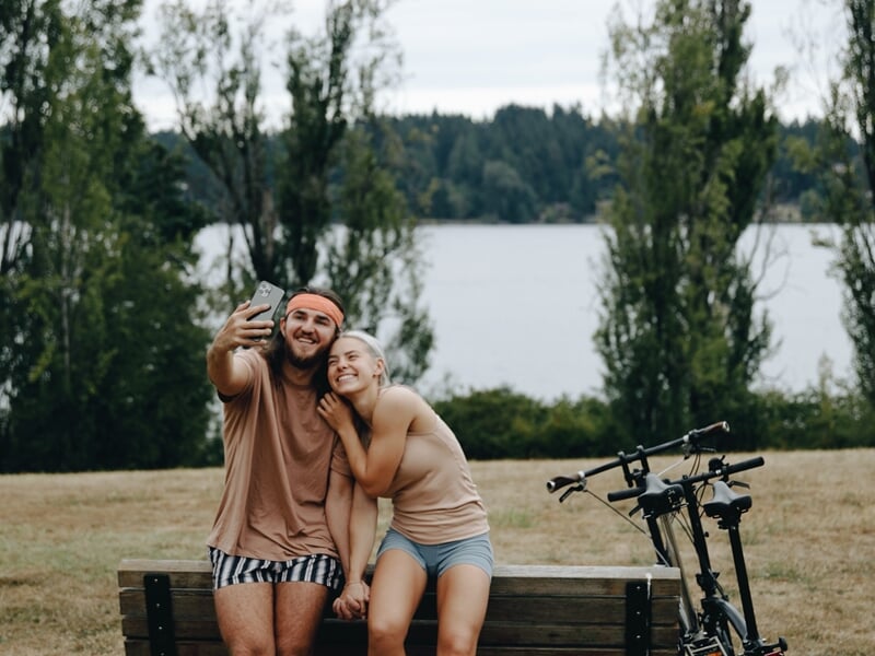 couple prenant un selfie devant un lac avec vélo électrique