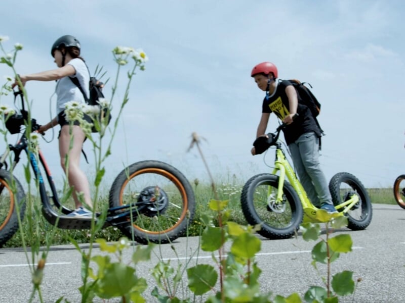 deux personnes en trottinette électrique sur route de campagne