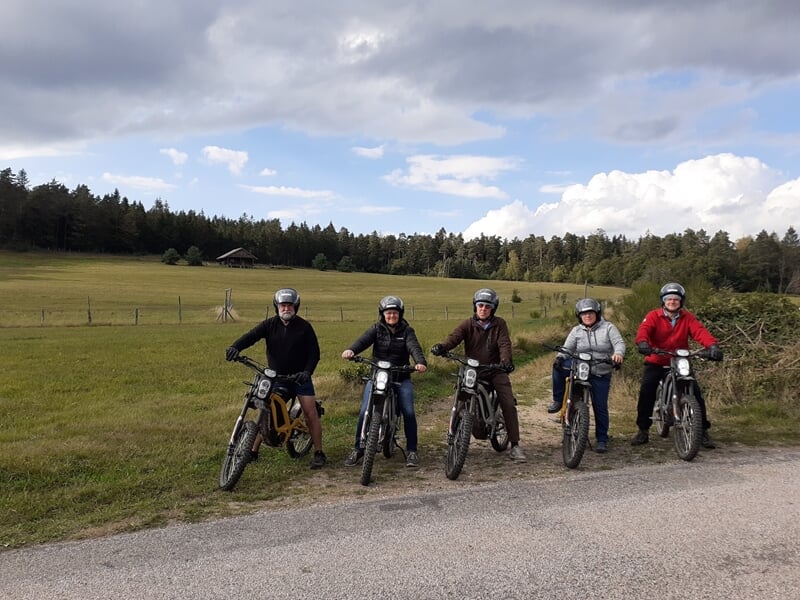 Groupe de cinq personnes à moto électrique sur un chemin de campagne.