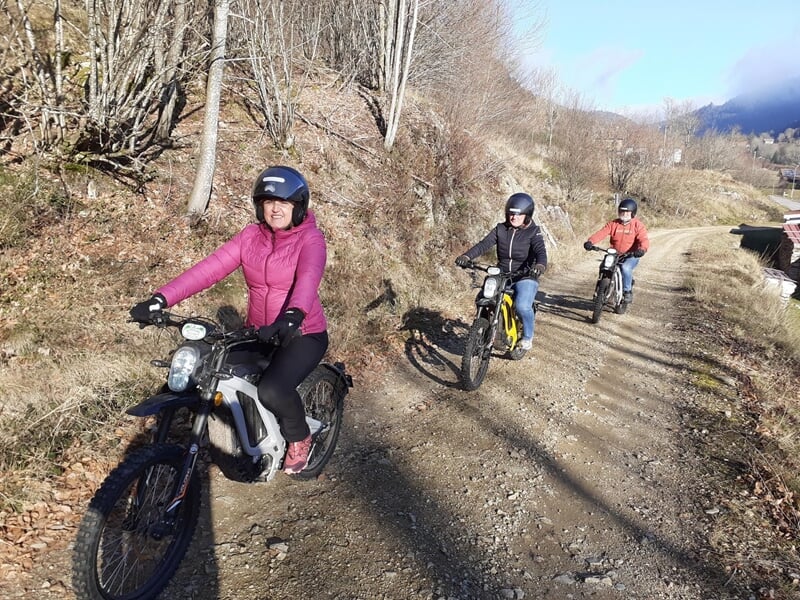 Groupe de trois personnes à moto électrique sur un chemin de campagne.