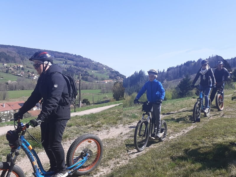 Famille en trottinette électrique sur un chemin avec vue sur les Vosges