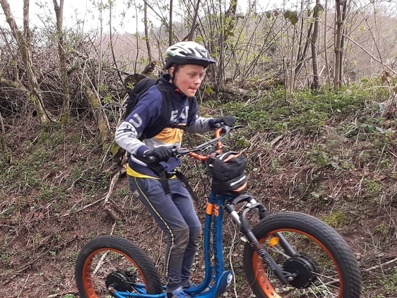 Garçon en trottinette électrique dans les bois