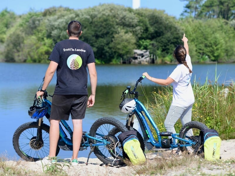 deux personnes en trottinette électrique devant un lac