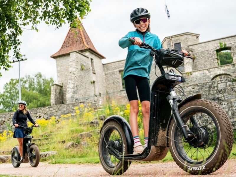 enfant en trottinette électrique à côté d'un petit village