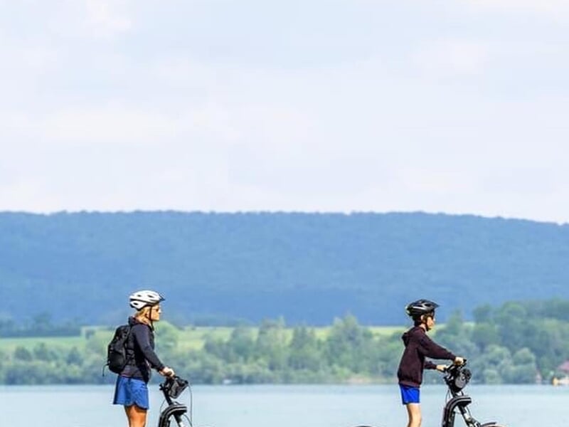 deux personnes en trottinette électrique devant un lac