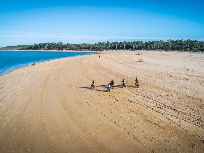 groupe de randonneurs en trottinettes électriques sur une plage de la côte atlantique