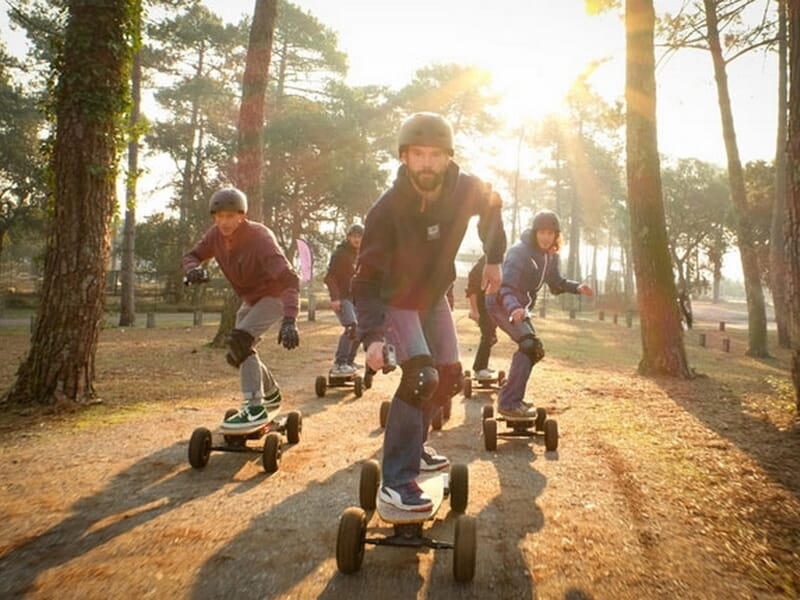 groupe d'hommes pratiquant le skate électrique dans une forêt